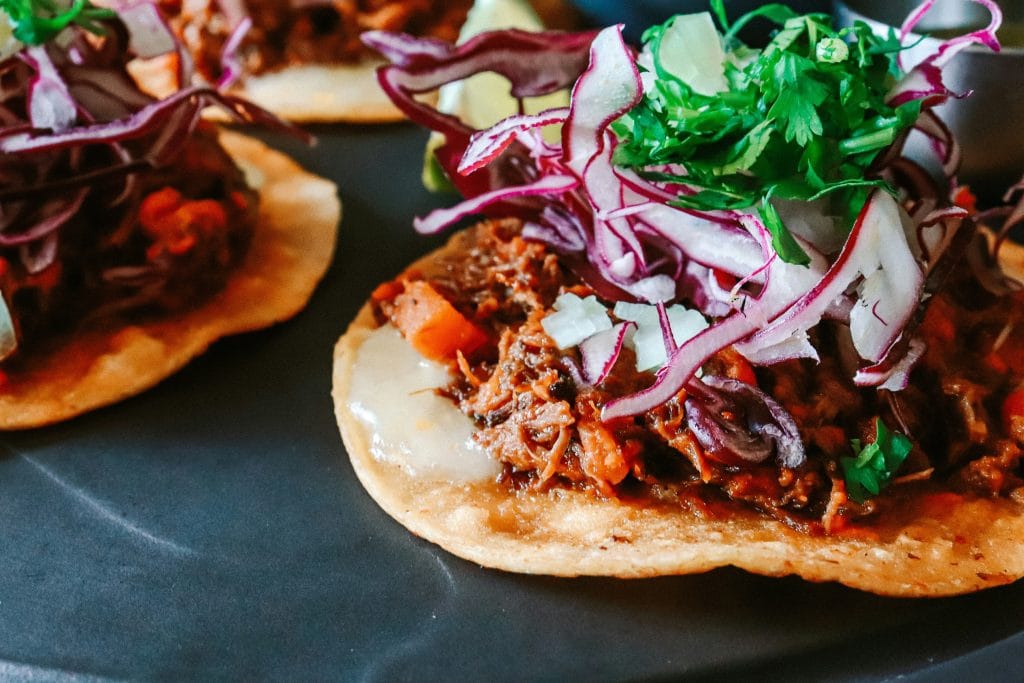 mexican chicken tostada with onion, julienne red cabbage, cheese, and cilantro